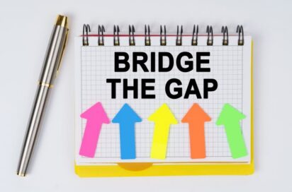 Colorful arrows pointing upward with 'Bridge the Gap' message on notepad.