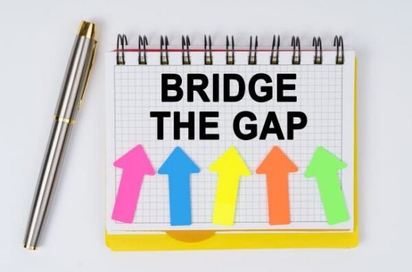 Colorful arrows pointing upward with 'Bridge the Gap' message on notepad.