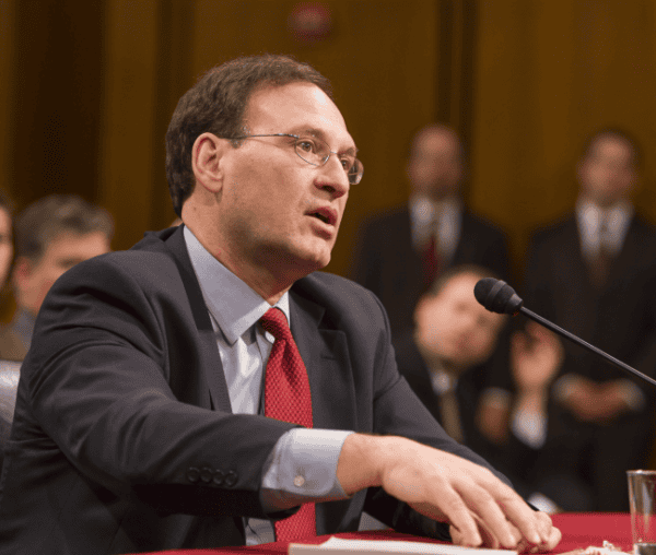 Justice Alito speaking at a formal legal event in a courtroom setting.
